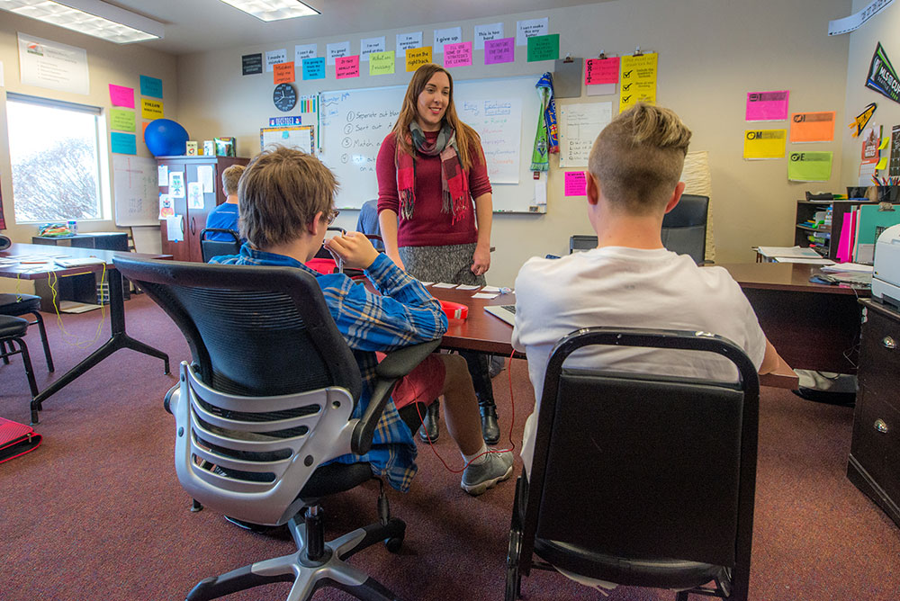 A teacher at WayPoint Academy's residential OCD treatment center works with two teens in a high school classroom | WayPoint Academy, an anxiety specific residential treatment program for teens and their families